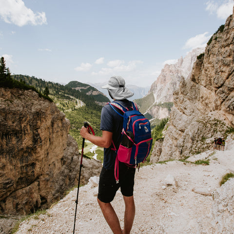 A man hiking with hiking poles, wearing the Sunday Afternoons Ultra Adventure Hat